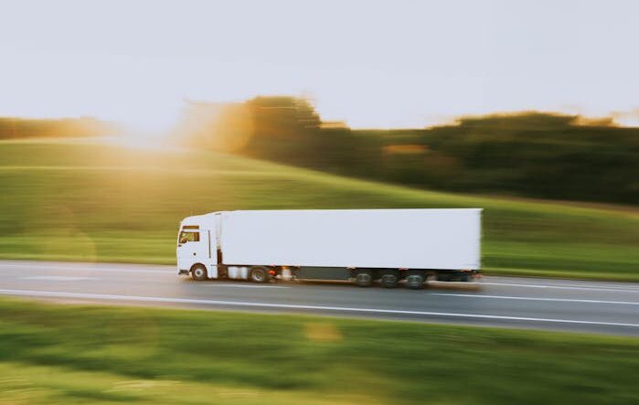 White cargo truck speeding through Vitebsk countryside at sunrise, symbolizing transportation and logistics.